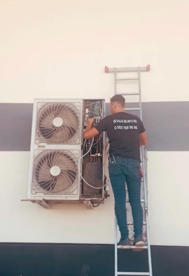 Merdiven üzerinde dış ünite bağlantılarını kontrol eden Sivari Elektrik teknisyeni