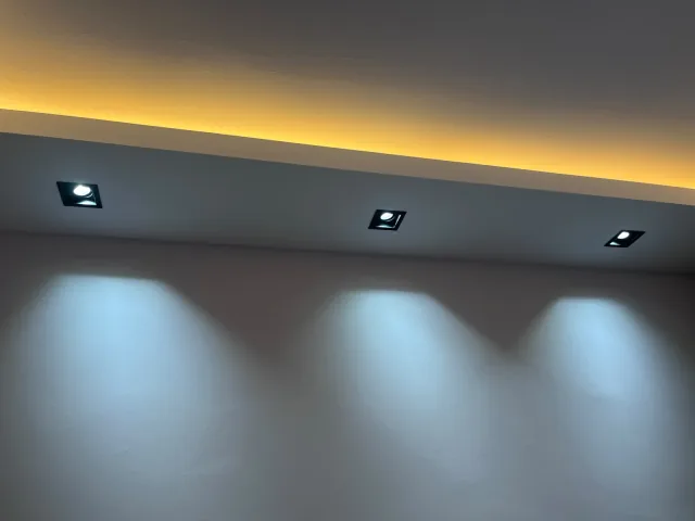 Sıcak tonlu gizli LED şerit ve kare spotlarla aydınlatılmış salon tavanı