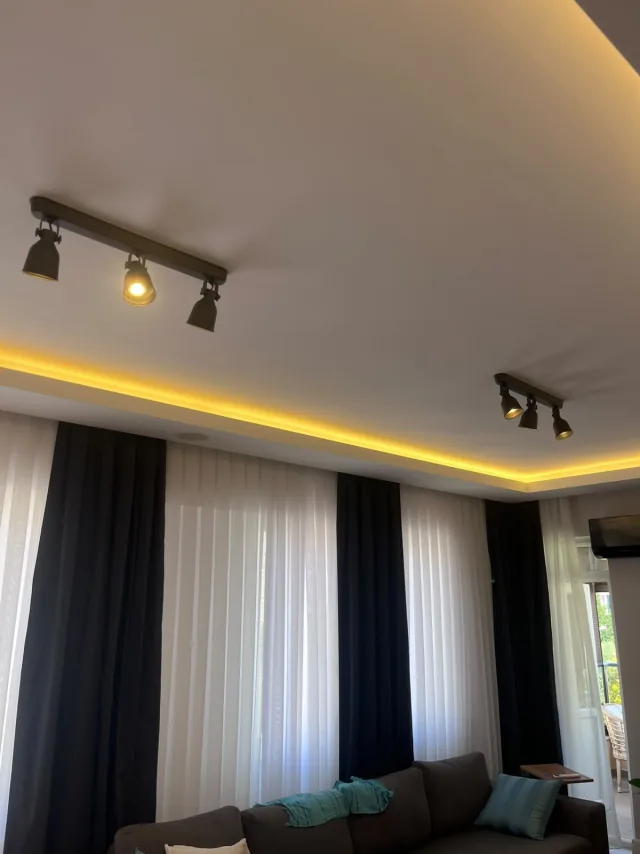 Ray spotlar ve sıcak tonlu gizli LED ile aydınlatılmış salon